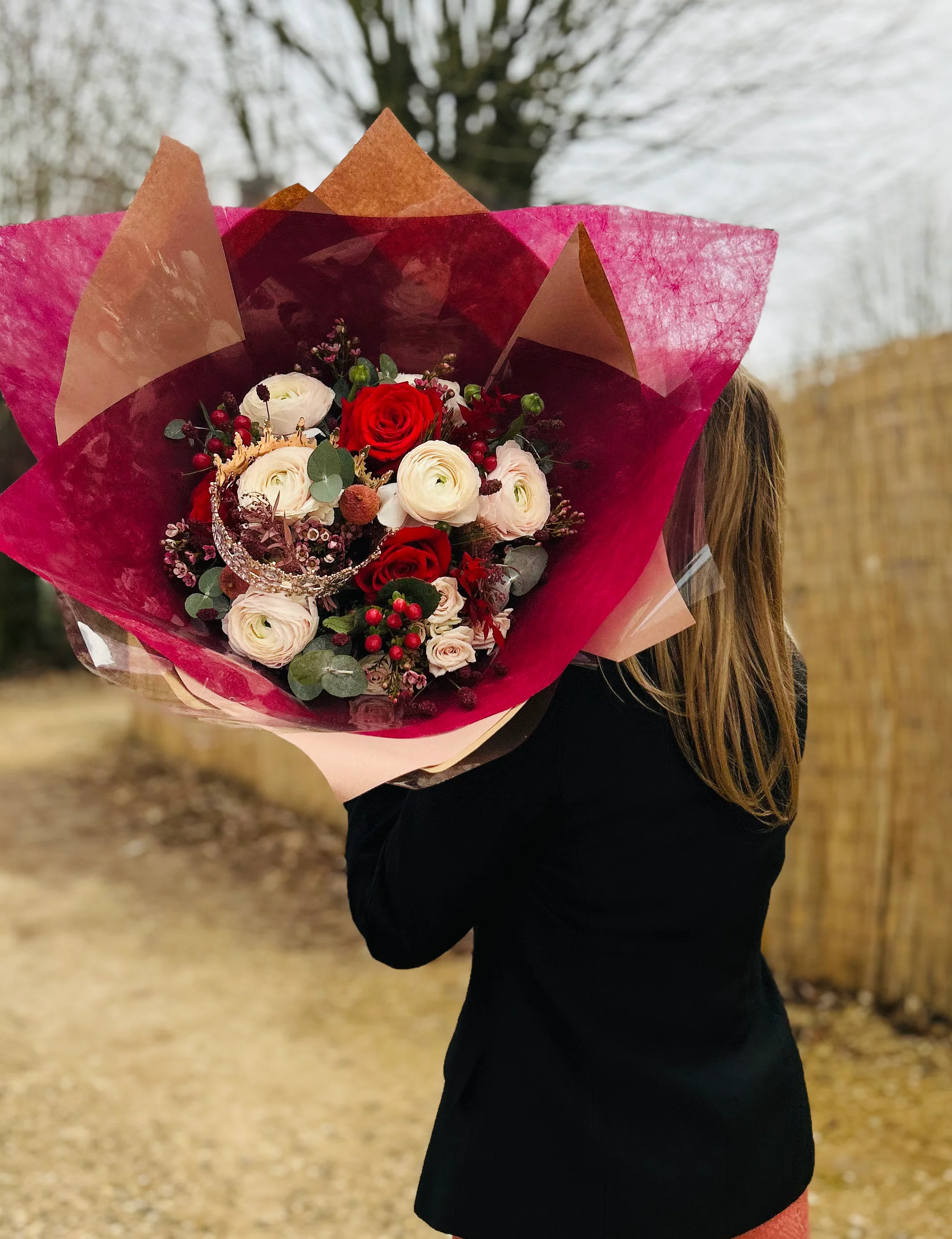 Créatrice de Maison L.I.C. tenant un grand bouquet aux tons rouges et crème