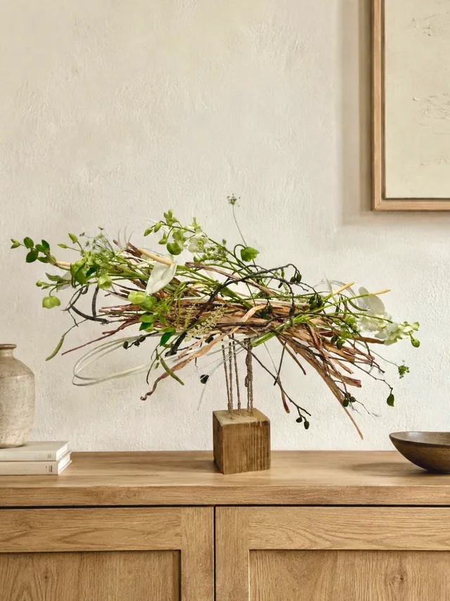 Composition végétale sculpturale dans un vase en bois